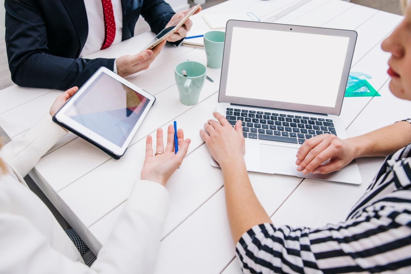 People collaborating around a workspace table with financial documents and laptops